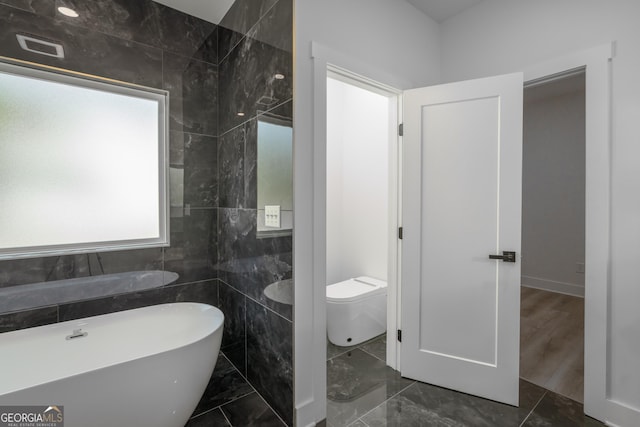 bathroom featuring toilet, tile walls, and a bath