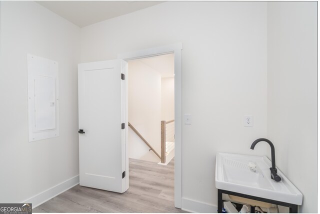 bathroom featuring electric panel, sink, and wood-type flooring