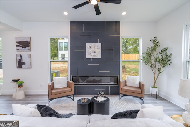 living room with hardwood / wood-style flooring, ceiling fan, a wealth of natural light, and a tiled fireplace