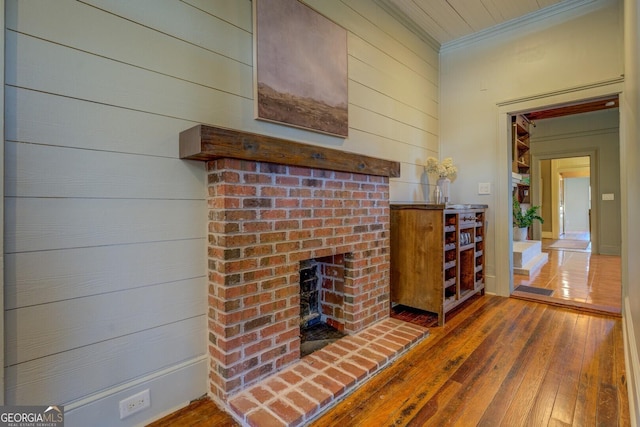 unfurnished living room with dark wood-type flooring, crown molding, and a fireplace