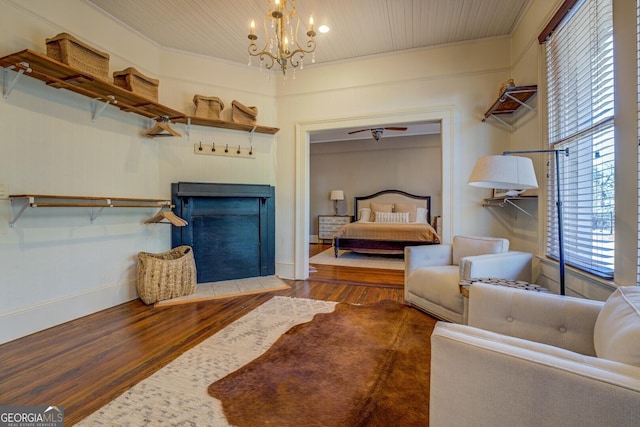 living room featuring a healthy amount of sunlight, a chandelier, crown molding, and dark hardwood / wood-style flooring