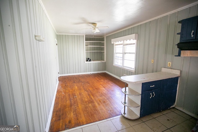 interior space with tile patterned flooring, ceiling fan, built in shelves, and crown molding