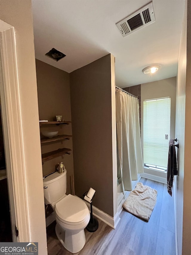 bathroom featuring hardwood / wood-style flooring, toilet, and a shower with curtain