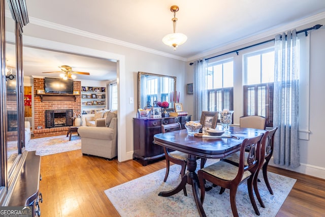 dining area featuring a fireplace, ceiling fan, hardwood / wood-style flooring, ornamental molding, and built in shelves