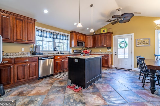 kitchen with light stone countertops, a center island, lofted ceiling, appliances with stainless steel finishes, and ceiling fan