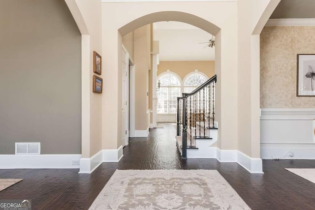 entrance foyer featuring dark wood-type flooring, ceiling fan, and ornamental molding