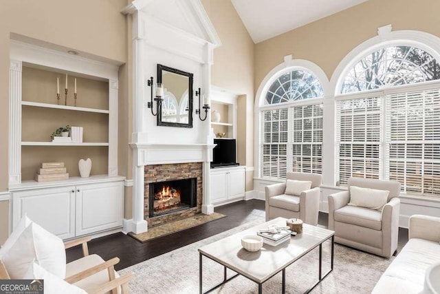 living room with a fireplace, built in features, vaulted ceiling, and dark hardwood / wood-style flooring