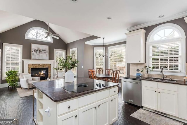 kitchen featuring white cabinets, dishwasher, black electric cooktop, a fireplace, and sink