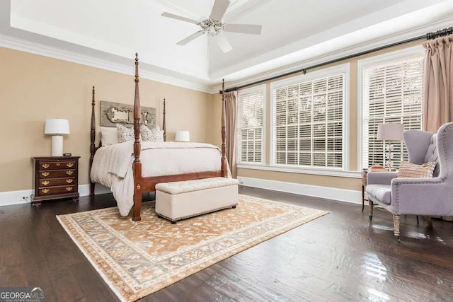 bedroom with ornamental molding, ceiling fan, a tray ceiling, and dark hardwood / wood-style flooring