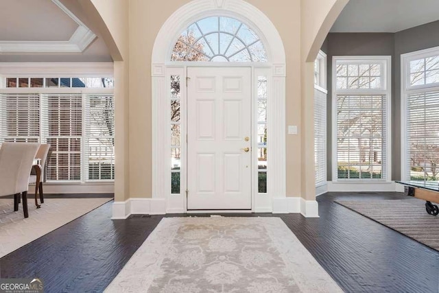 foyer with dark wood-type flooring and crown molding