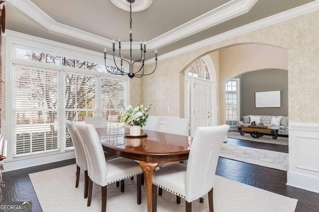 dining area with a chandelier, ornamental molding, a tray ceiling, and dark hardwood / wood-style flooring