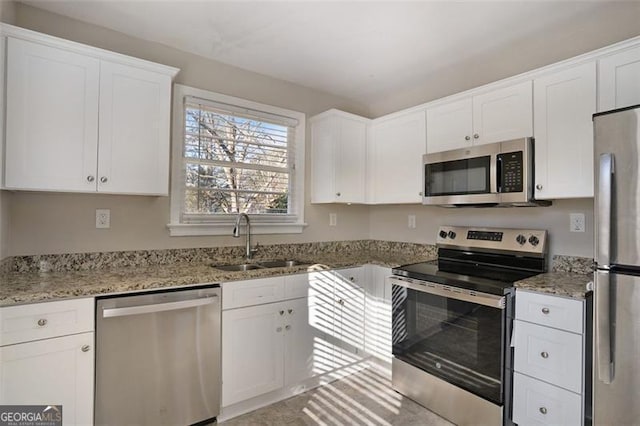 kitchen featuring sink, white cabinets, light stone countertops, and appliances with stainless steel finishes