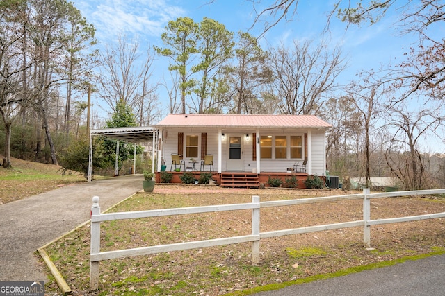 view of front facade with a porch, a carport, and central AC unit