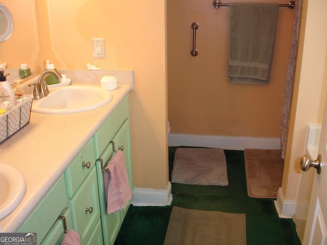 full bathroom with double vanity, baseboards, and a sink