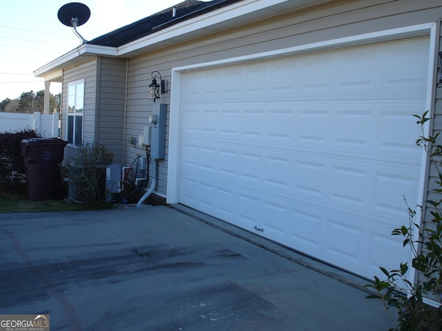 garage featuring driveway and fence