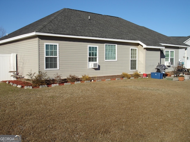 back of house with a shingled roof and a lawn