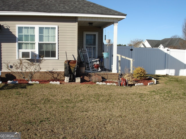 property entrance with a porch, cooling unit, a shingled roof, fence, and a lawn