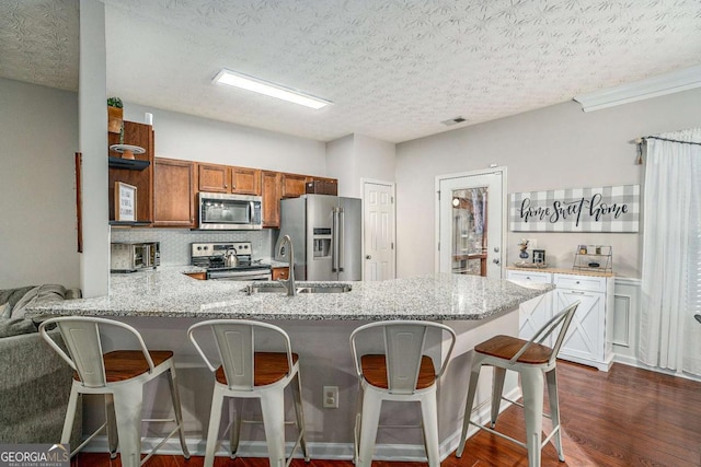 kitchen featuring a breakfast bar area, kitchen peninsula, a textured ceiling, and appliances with stainless steel finishes