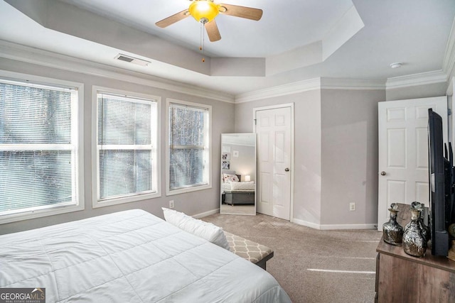 bedroom featuring ceiling fan, a raised ceiling, light colored carpet, and multiple windows