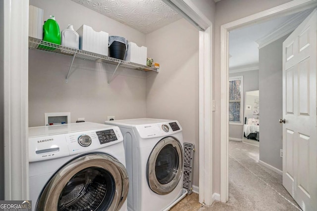 clothes washing area featuring ornamental molding, washer and dryer, light colored carpet, and a textured ceiling