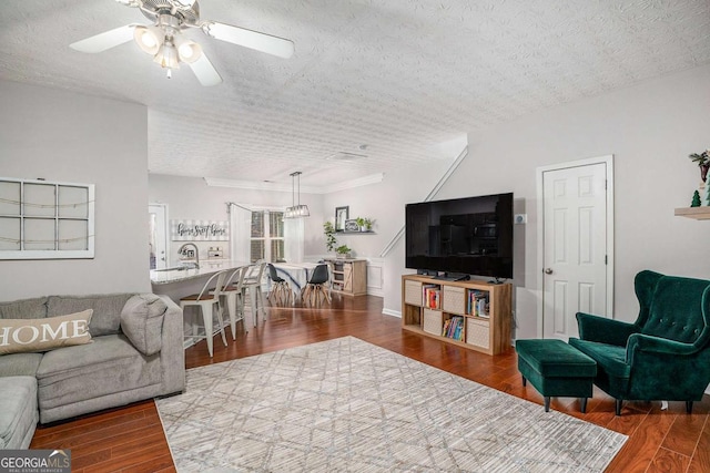 living room featuring crown molding, hardwood / wood-style floors, a textured ceiling, and ceiling fan