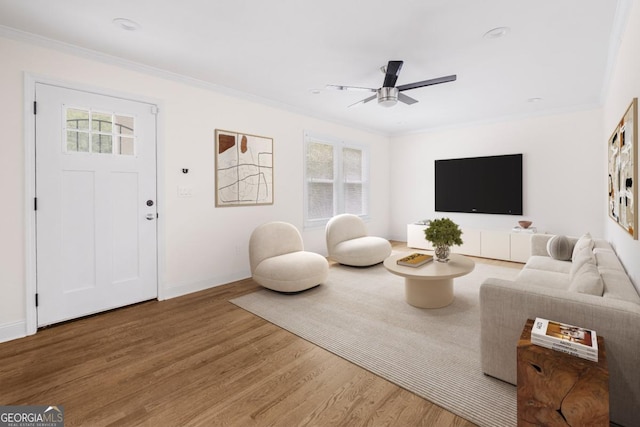 living room featuring wood-type flooring, ornamental molding, and a healthy amount of sunlight