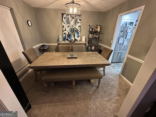 dining area with a textured ceiling, a chandelier, and carpet flooring