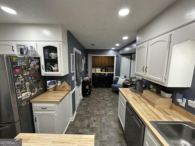 kitchen featuring butcher block counters, stainless steel fridge, white cabinetry, separate washer and dryer, and black dishwasher