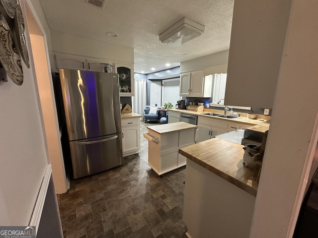 kitchen with sink, white cabinets, kitchen peninsula, a kitchen island, and appliances with stainless steel finishes