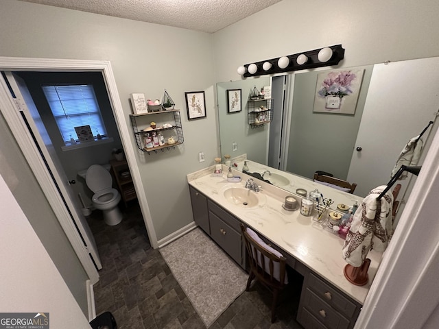 bathroom featuring a textured ceiling, vanity, and toilet