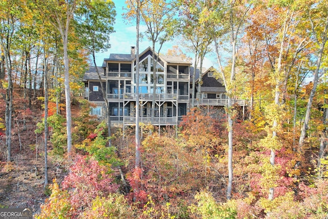 rear view of property with a sunroom and a balcony