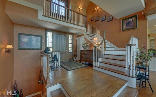 entryway with hardwood / wood-style floors and a towering ceiling