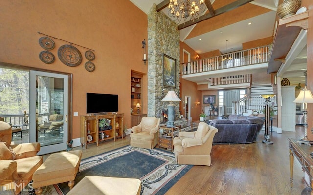 living room featuring a notable chandelier, built in shelves, wood-type flooring, and high vaulted ceiling