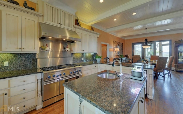 kitchen featuring sink, hanging light fixtures, beamed ceiling, range hood, and range with two ovens