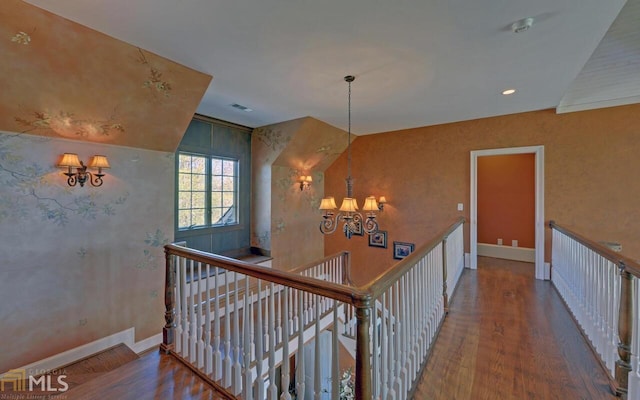 corridor with wood-type flooring and a notable chandelier