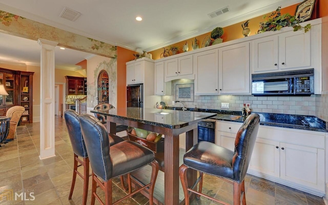 kitchen featuring a breakfast bar, decorative columns, white cabinets, decorative backsplash, and black appliances