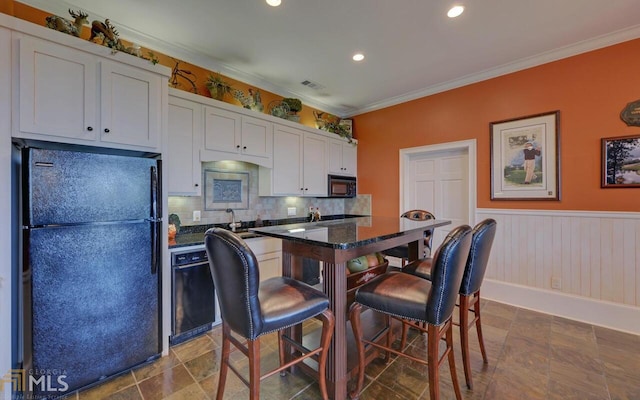 kitchen featuring a breakfast bar, crown molding, black appliances, a center island, and white cabinets