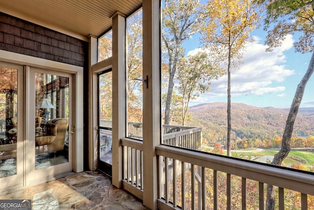 unfurnished sunroom with a mountain view, wooden ceiling, and a healthy amount of sunlight