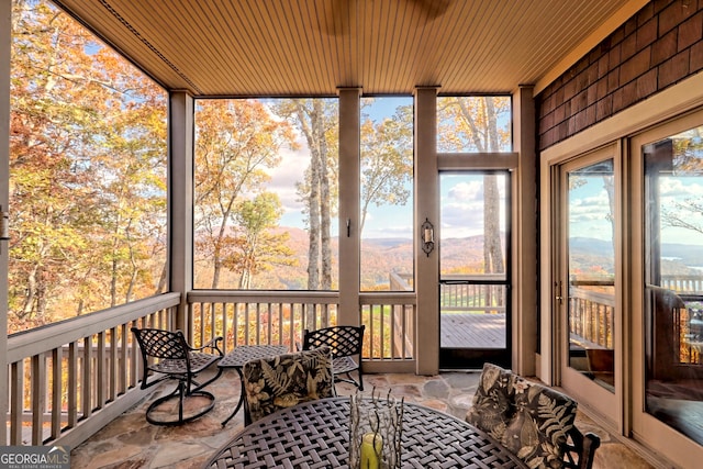 sunroom / solarium featuring a mountain view, wood ceiling, and a healthy amount of sunlight