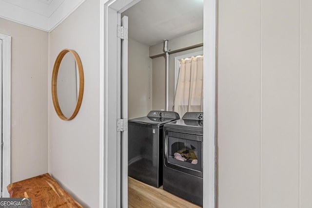 clothes washing area featuring washing machine and clothes dryer and light hardwood / wood-style floors