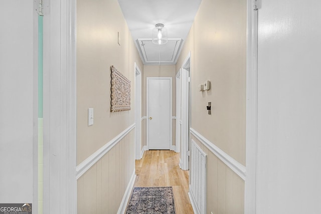 hallway with ornamental molding and light hardwood / wood-style floors