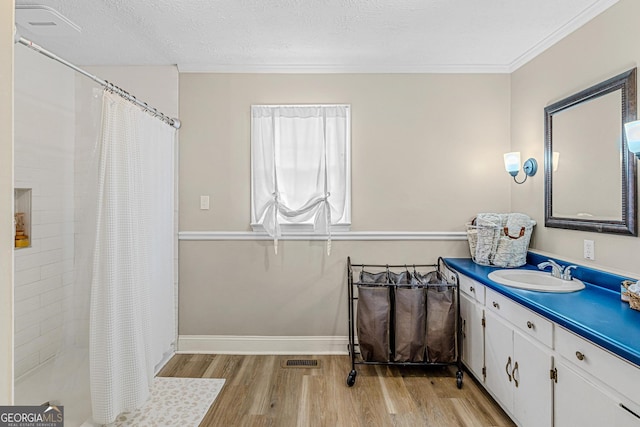 bathroom featuring hardwood / wood-style floors, vanity, crown molding, a textured ceiling, and a shower with curtain