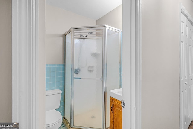 bathroom featuring tile walls, vanity, toilet, and walk in shower