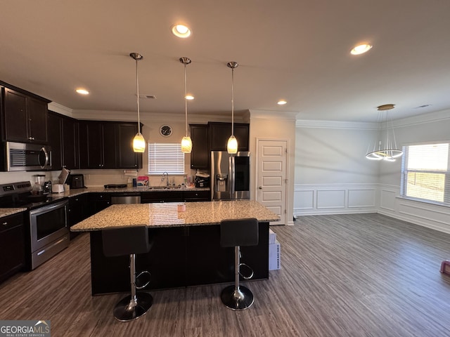 kitchen with decorative light fixtures, crown molding, a center island, and stainless steel appliances