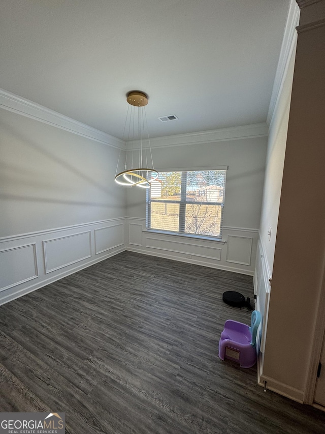 unfurnished dining area featuring dark wood-type flooring, crown molding, and a notable chandelier