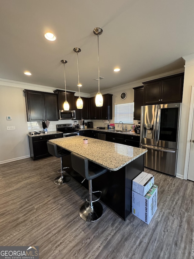 kitchen featuring a center island, dark hardwood / wood-style flooring, stainless steel appliances, a kitchen breakfast bar, and hanging light fixtures