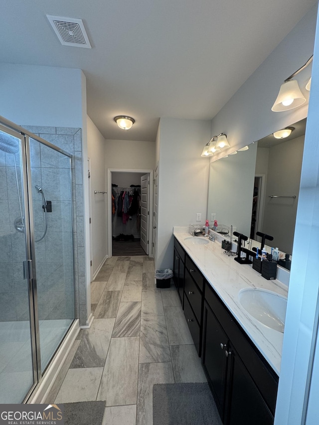 bathroom with a shower with shower door and vanity