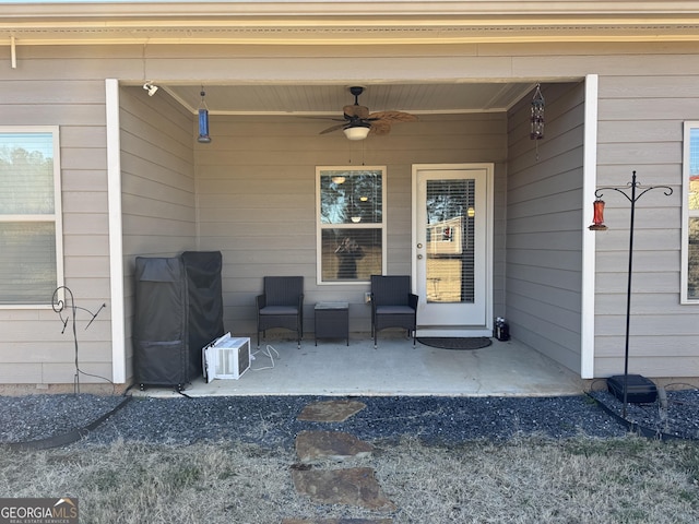 view of exterior entry with ceiling fan and a patio