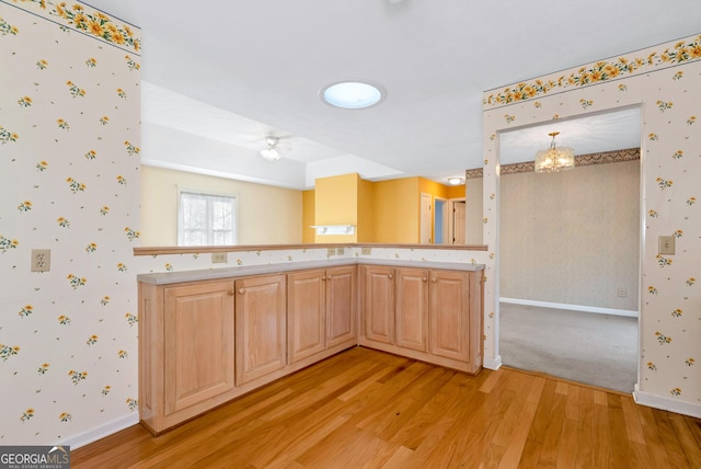 kitchen with light brown cabinets, a notable chandelier, and light hardwood / wood-style flooring