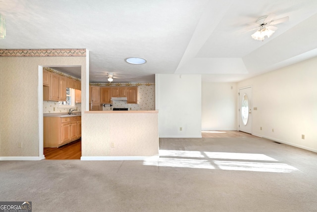 kitchen featuring sink, decorative backsplash, ceiling fan, light carpet, and light brown cabinets